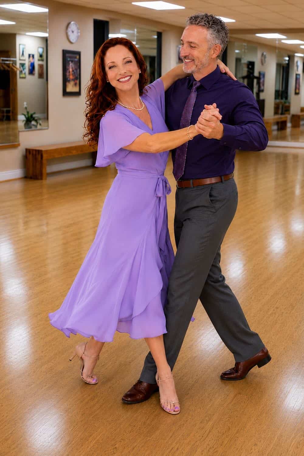 Happy couple dancing in a dance studio with wooden floors and framed pictures on the wall.